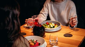 Zwei Personen sitzen an einem Tisch und essen Risotto und ein Nudelgericht